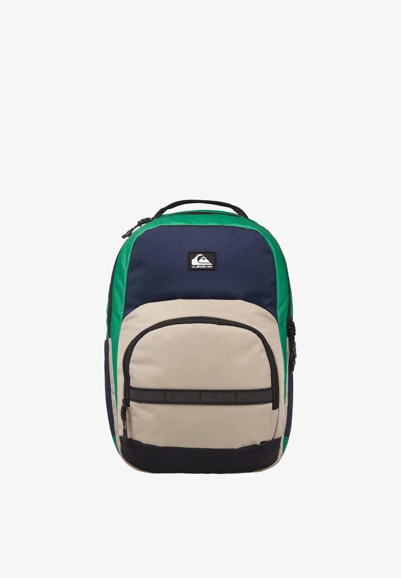 Sac à dos bleu marine, vert et beige avec un compartiment principal et une poche avant, doté d'une fermeture éclair noire et d'un patch logo.