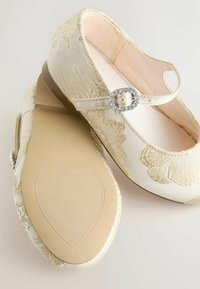 Ballettschuhe in Cremefarbe mit floraler Stickerei, weichem Stoffobermaterial, Riemendetail mit Schmuckakzent und strukturierter, herzförmiger Gummisohle.