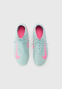 Nike fotbollsskor i teal med rosa accenter, med en texturerad yta, snörning och en låg profil.