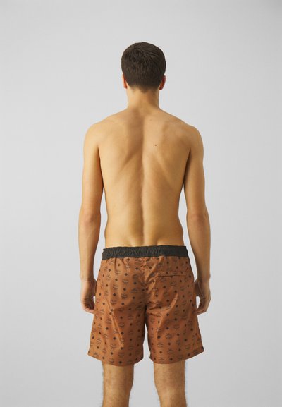Pantaloni de baie maro cu un brâu elastic negru, având un model negru repetitiv pe un material texturat. Vederea din spate arată o croială lejeră.