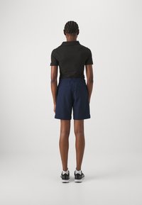 Polo noir à manches courtes, associé à un short marine. La tenue comprend une taille élastique et deux poches arrière.