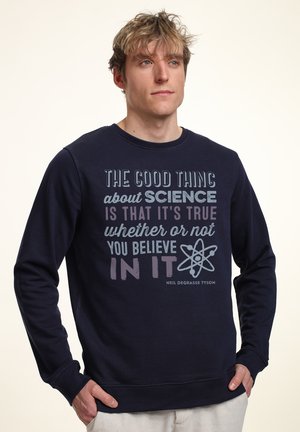 Navyblaue Sweatshirt aus Baumwollmischung, mit einem Frontdesign aus Text in verschiedenen Farben, einschließlich einer stilisierten Atomgrafik und Zitatzuweisung.