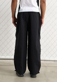 YOURTURN by Zalando UNISEX - Donji dijelovi trenirke - black