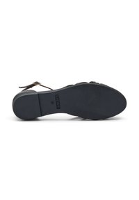Sandalia negra con suela texturizada, correa ajustable y un leve tacón. Presenta un material superior suave y una suela con marca.