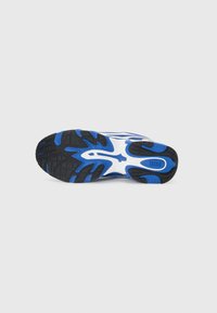Sneaker with a black and blue rubber sole, featuring a white mesh upper and distinctive pattern, providing texture and grip.