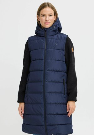 Marineblå puffervest med hette, med en quiltet design, glidelås foran og sidelommer. Svarte fleece-ermer med en rund applikasjon.