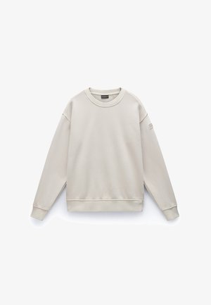 Beige sweatshirt met een ronde halslijn, lange mouwen en geribbelde manchetten. Gemaakt van zachte stof, met een klein logo-patch op de mouw.