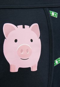 Dunkelblauer Stoff mit einem pinken Sparschwein-Graphic und einem lächelnden Gesicht. Enthält grüne Dollarschein-Akzente am Hüftbund.