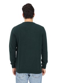 Maglione lavorato a maglia verde scuro con maniche lunghe, collo rotondo e polsini a coste, visto da dietro. Texture liscia, design semplice.