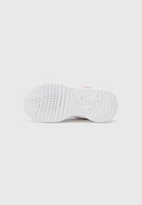 Weiße Sneaker-Sohle mit strukturiertem Grip-Muster und Belüftungsöffnungen. Besitzt einen dezenten rosa Akzent in der Nähe der Ferse. Sauberes, abgerundetes Design.