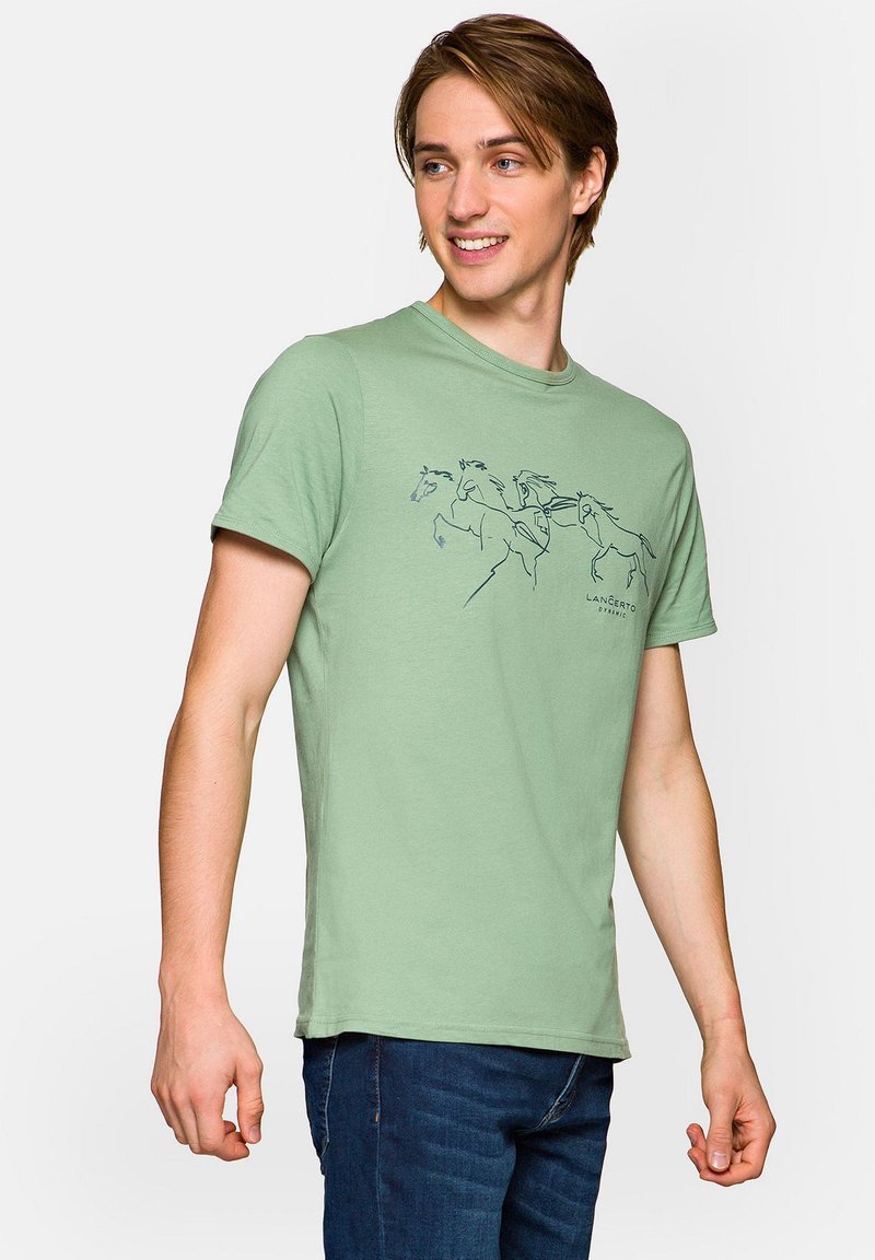 Zielona bawełniana koszulka z grafiką konia w kolorze granatowym. Krótkie rękawy, okrągły dekolt i luźny krój. Nosić z niebieskimi dżinsami.