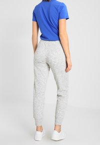 Grå sweatpants med elastisk midjeband och mudd, med en mjuk yta. Kombinerat med en enfärgad blå t-shirt. Vita sneakers synliga.