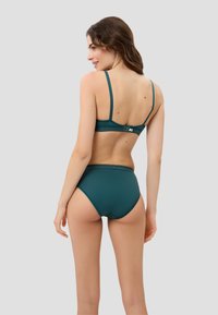 Türkises Bikini-Set mit einem Bandeau-Oberteil und hochgeschnittenen Unterteilen. Verfügt über verstellbare Träger und einen Hakenverschluss auf der Rückseite. Glatte Textur.