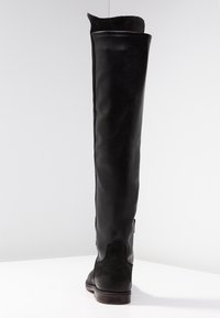 Bota negra hasta la rodilla con un exterior de cuero liso, textura sutil, puntera redondeada y un tacón bajo apilado con cremallera lateral.