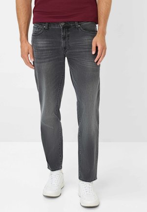 Grijze denim jeans met een taps toelopende pasvorm, voorzien van subtiele vervaging en een klassieke vijf-pocket ontwerp. Combinatie met witte sneakers.