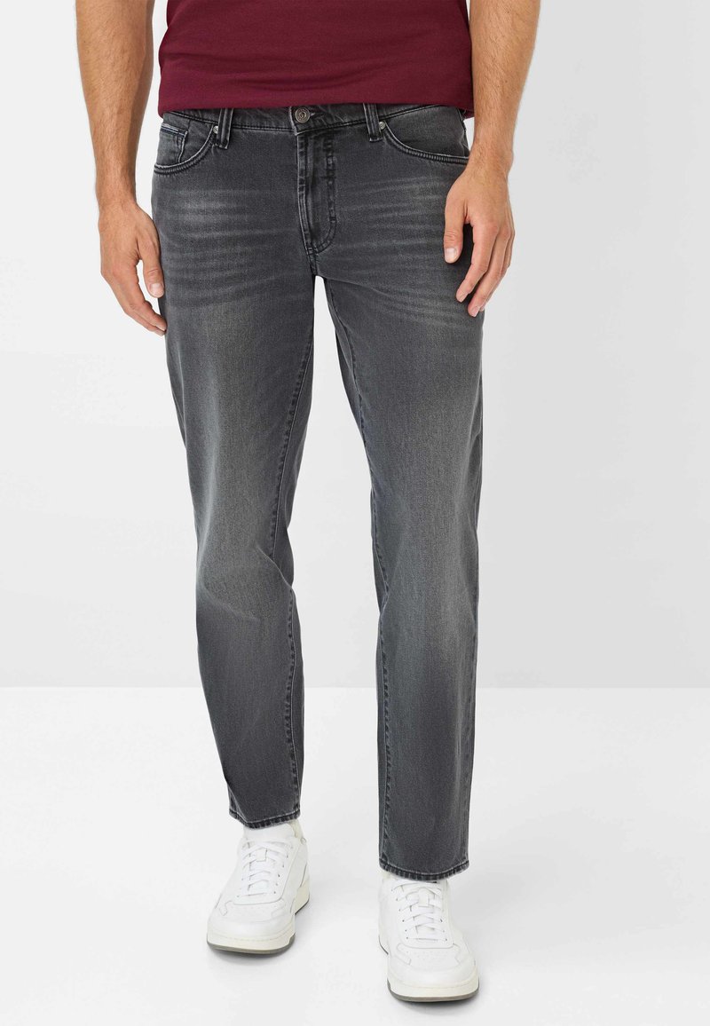 Jeans in denim grigio con vestibilità affusolata, caratterizzati da una leggera sbiaditura e un classico design a cinque tasche. Abbinati a sneakers bianche.