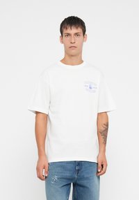 Witte katoenen t-shirt met een ronde hals en korte mouwen, voorzien van een paarse grafische print van "ONLY & SONS" met een cartoon.