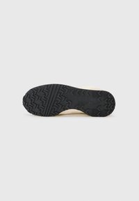 Talpa din cauciuc negru cu un model texturat de profil. Partea superioară are o nuanță bej deschis, textură netedă și un design minimalist.