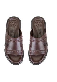 Bruine leren sandalen met twee brede banden, een geprofileerde voetbed en een gekantelde zwarte zool. Kenmerken zijn gestikte details en een hexagonaal logo.