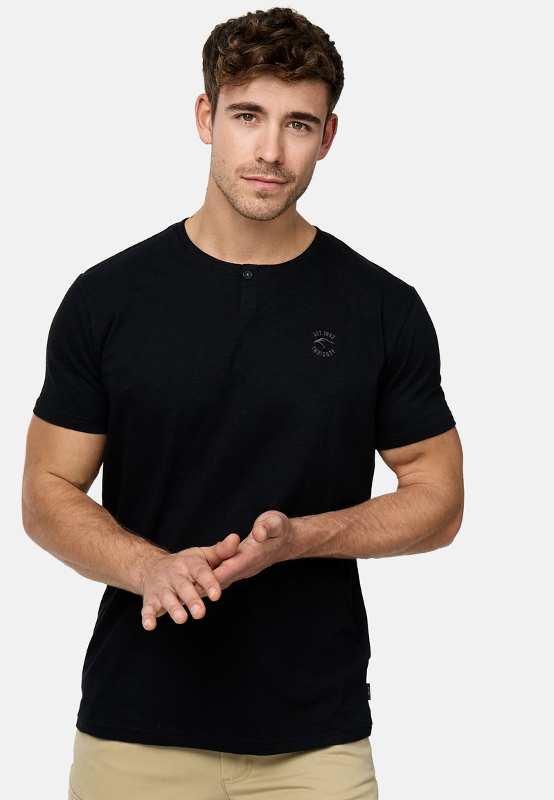 Crni kratki rukav Henley majica od pamuka, s okruglim izrezom, dvostrukim dugmetom i malim logotipom na prsima.