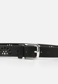 Zwarte leren riem met decoratieve uitsparingen en een zilverkleurige metalen gesp. Gladde textuur met gaatjes voor verstelbaarheid.