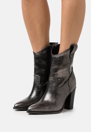 Bottines noires métalliques à bout pointu, en cuir texturé, avec un talon épais. Présente des coutures sur les côtés et une discrète languette.