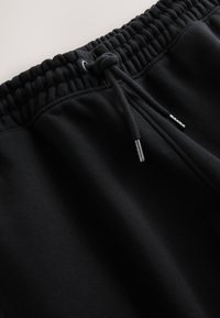 Suletud lähedalt mustast elastset vöökohast, millel on nöör ja metallist lõpud pehmetel kangast pükstel.