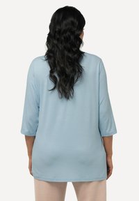 Helles Blau, locker sitzendes Oberteil mit drei Viertelärmeln, aus weichem Material gefertigt, mit einem runden Ausschnitt und einem geraden Saum.