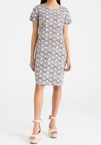 Kortärmad klänning med cirkelmönster i marinblått, beige och krämfärgat. Tillverkad av ett strukturerat tyg, figursydd silhuett, knälängd.