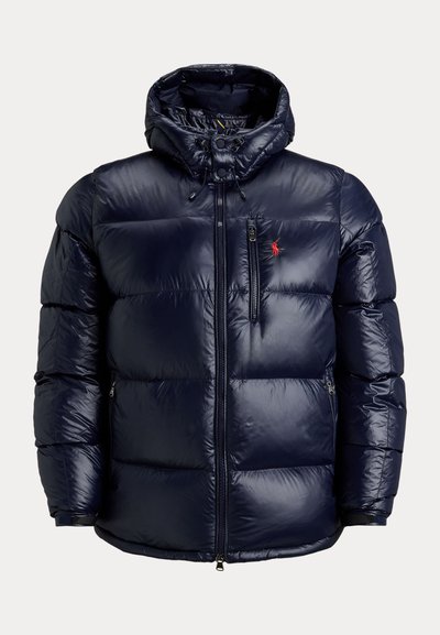 Námornícka modrá prešívaná bunda s kapucňou, plný predný zips, zips na hrudníku, bočné vrecká a červené vyšívané logo na hrudi.