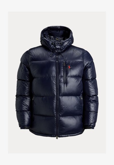 Σακάκι πούφφερ ναυτικού μπλε χρώματος με κουκούλα, πλήρης μπροστινός φερμουάρ, τσέπη στο στήθος με φερμουάρ, πλαϊνές τσέπες και κόκκινο κεντημένο λογότυπο στο στήθος.