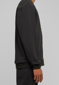 Donkergrijze sweatshirt met een ronde halslijn, ribgebreide manchetten en zoom. Gemaakt van zachte stof, met een eenvoudig, strak ontwerp.