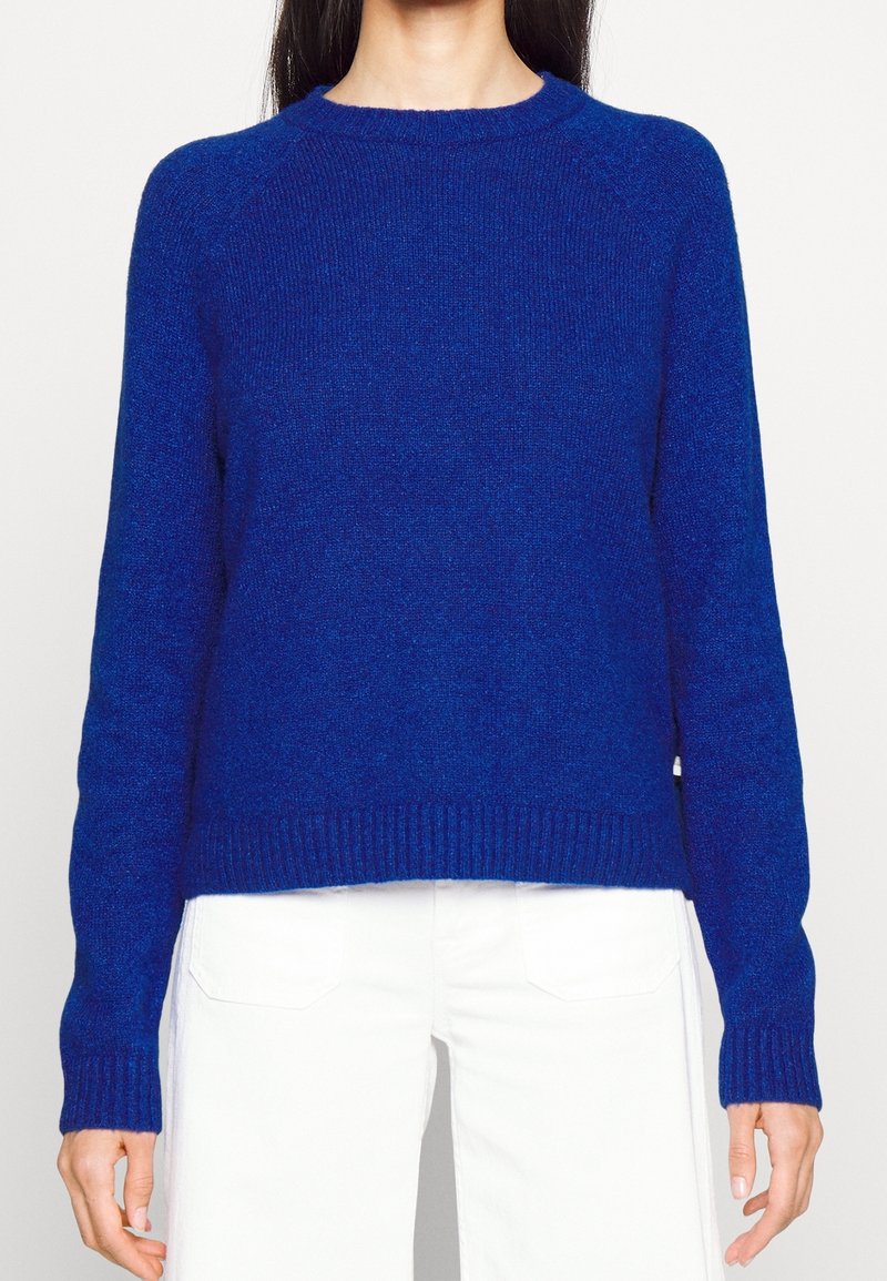 Modrý pletený svetr s kulatým výstřihem, žebrovanými manžetami a lemem. Má mírně volný střih a texturovanou látku.