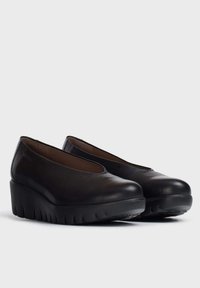 Zapatos de cuña de cuero negro con puntera redonda, abertura superior elástica y suela de goma texturizada. Acabado suave con un ligero brillo.