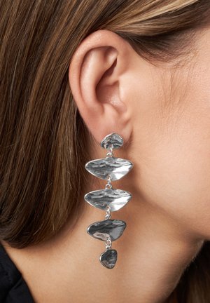 Sølv, hængende øreringe med et forskudt design, der har fem polerede, abstrakte former forbundet af små led.