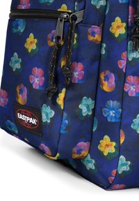 Blå ryggsäck från Eastpak med blommönster, flerfärgade blommor, dragkedjor och svart varumärkesskylt. Tillverkad av slitstarkt tyg med texturerad yta.