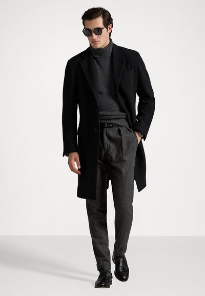 Black wool overcoat, gray turtleneck, gray trousers, black shoes, and sunglasses. Textured fabric with tailored fit and neutral colors.