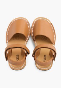 Słomkowe skórzane sandały o otwartym wzorze, z białymi przeszyciami i regulowanym paskiem. Gładka tekstura i okrągły czubek.