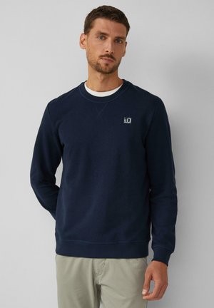 Marineblå sweatshirt med rund hals, ribbede manchetter og kant. Har et lille logo på brystet. Fremstillet af blødt, struktureret stof.