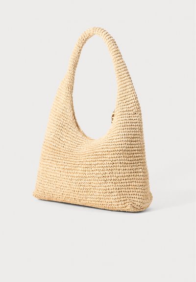 Woven straw shoulder bag in beige with a rounded handle and soft, slouchy shape, featuring an open top and textured surface.