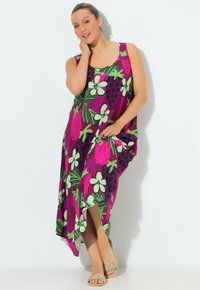 Lila ärmlös klänning med stora blommönster och frukter i rosa och grönt, med sidospalt och ledig passform. Kompletteras med sandaler.