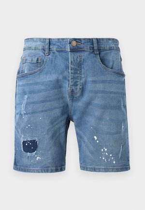 Denim shorts in light blue, featuring distressed details, a large patch at the left thigh, and white paint splatters for accent.