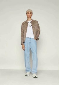 Suknja od svjetlucavog suede materijala, bijela majica s grafičkim detaljem, svijetloplave široke traperice i bijele tenisice s crnim naglascima.