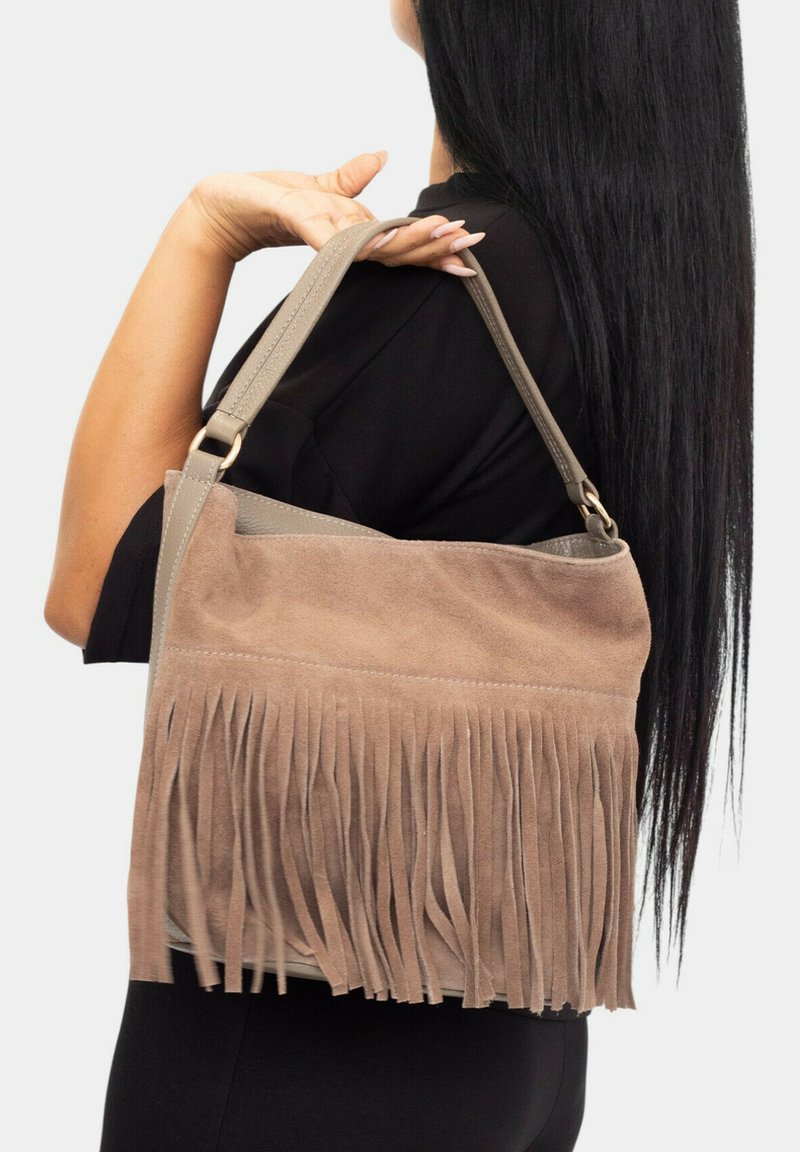 Bolso de ante en beige con detalles de flecos en la parte inferior. Incluye una correa gris con herrajes dorados, con una textura suave.