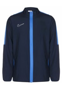 Marineblauwe jas met lichtblauwe accenten, voorkant met rits, hoge kraag en zijzakken. Bevat een wit Nike-logo op de borst.