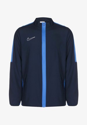 Navy blue jacket with light blue accents, front zipper, high collar, and side pockets. Features a white Nike logo on the chest.