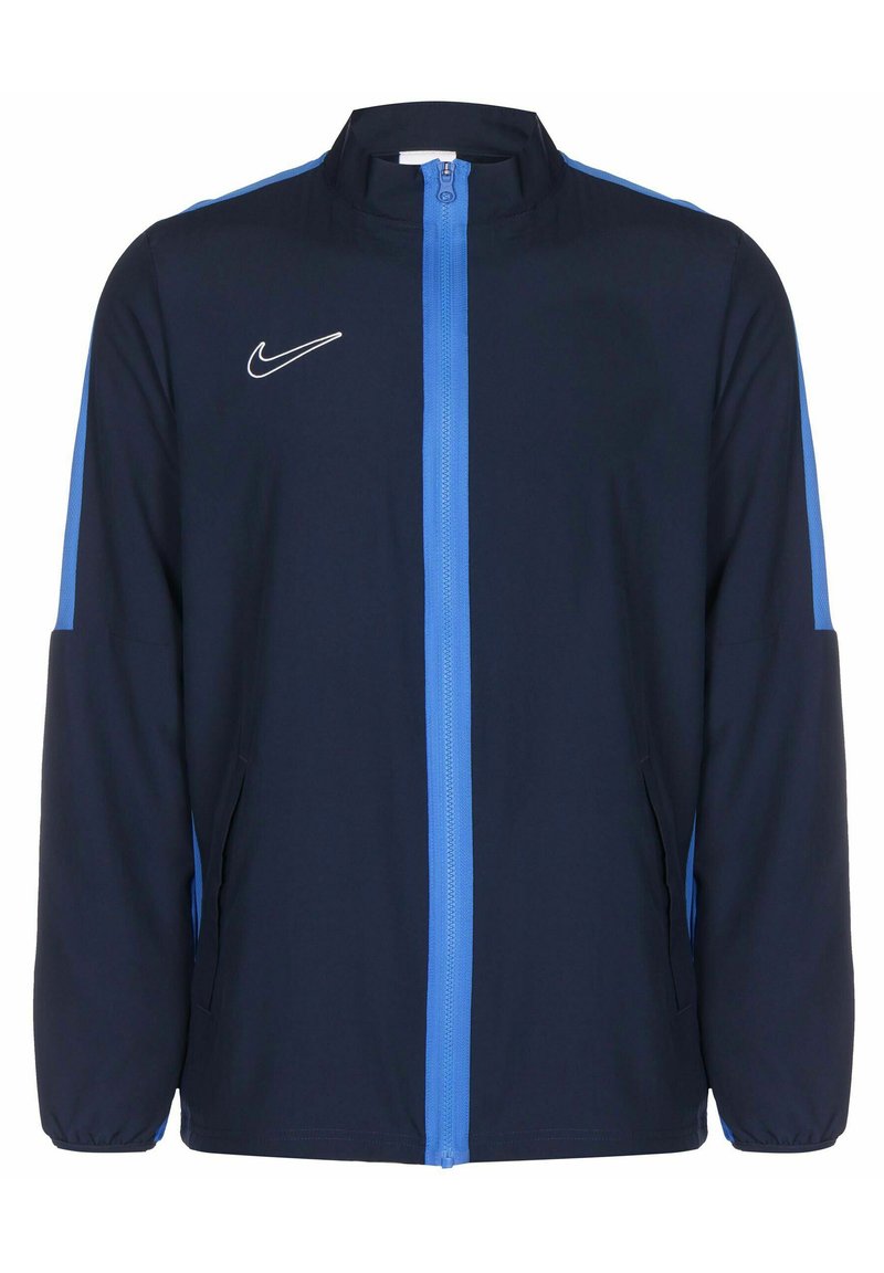 Marineblauwe jas met lichtblauwe accenten, voorkant met rits, hoge kraag en zijzakken. Bevat een wit Nike-logo op de borst.
