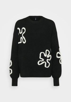 Svart strikket genser med hvite strukturerte blomsterdesign på ermene og foran, med rund halslinning og ribbestrikkede mansjetter.