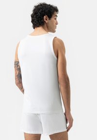 White tank top and shorts in soft fabric. Tank features round neckline, sleeveless design, and relaxed fit. Minimalist appearance with no patterns.