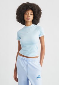 Jasnoniebieska sportowa koszulka z krótkimi rękawami, z delikatnym logo Nike w kolorze srebrnym, w połączeniu z jasnoniebieskimi spodniami dresowymi z grafiką tekstową.